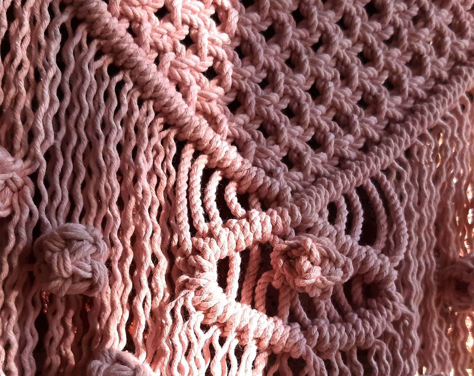 Tejido de macramé color rosa con un diseño de ojo en medio