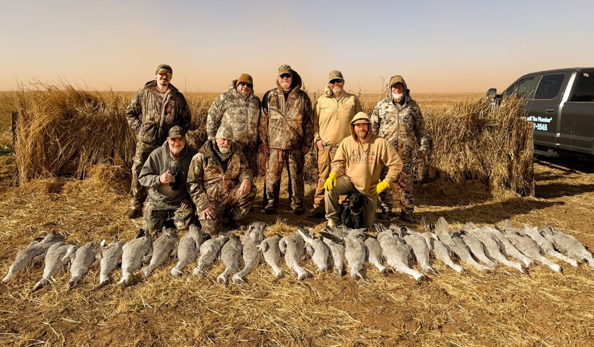 Group of hunters kneeling with their harvest in front of a hunting blind in a Texas field.