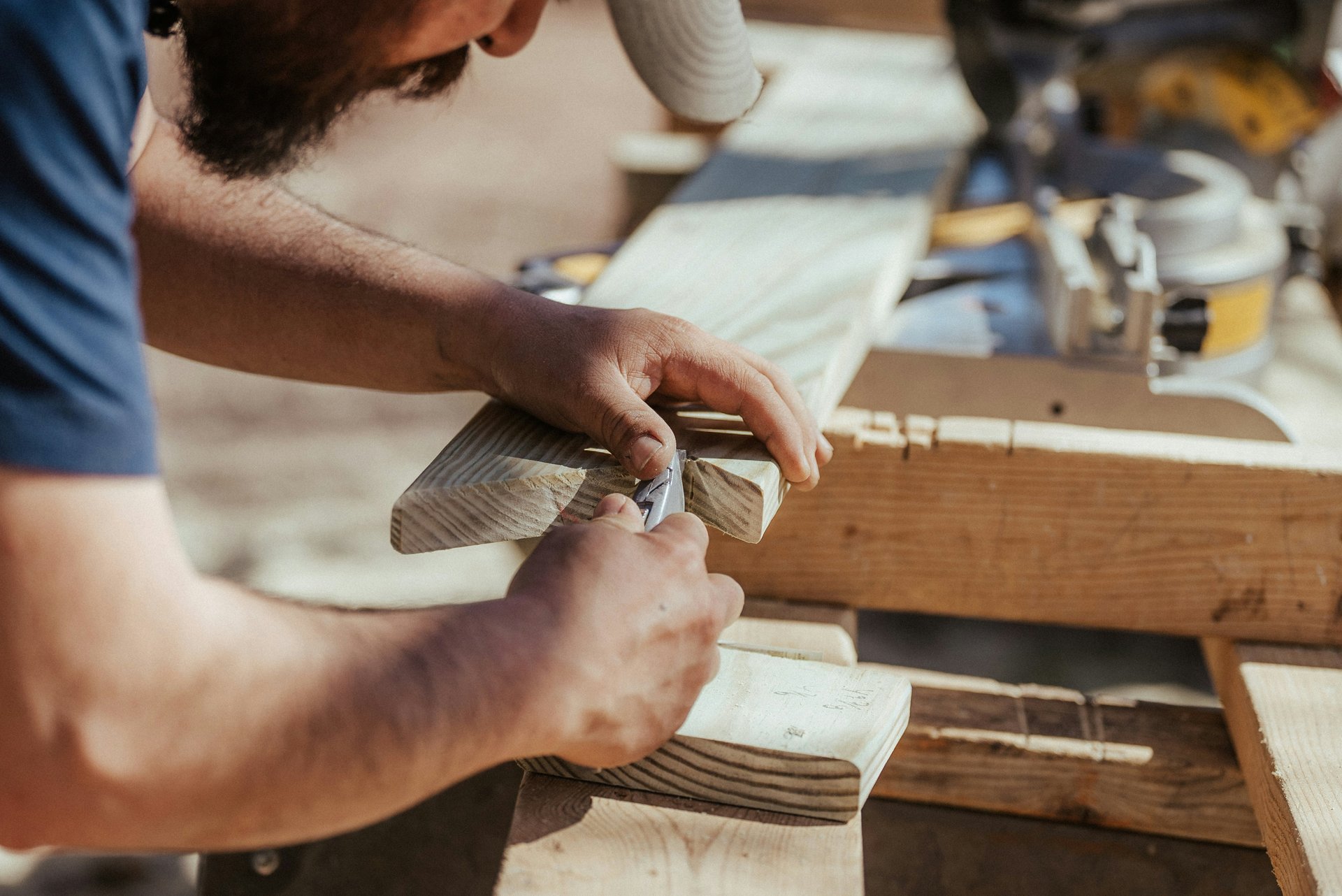 A man sanding a wooden table with a sander