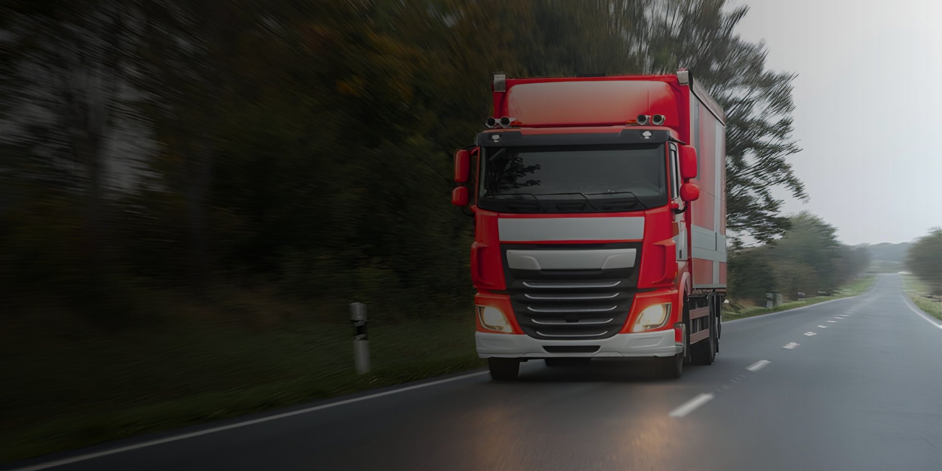A red semi truck driving down a rural road