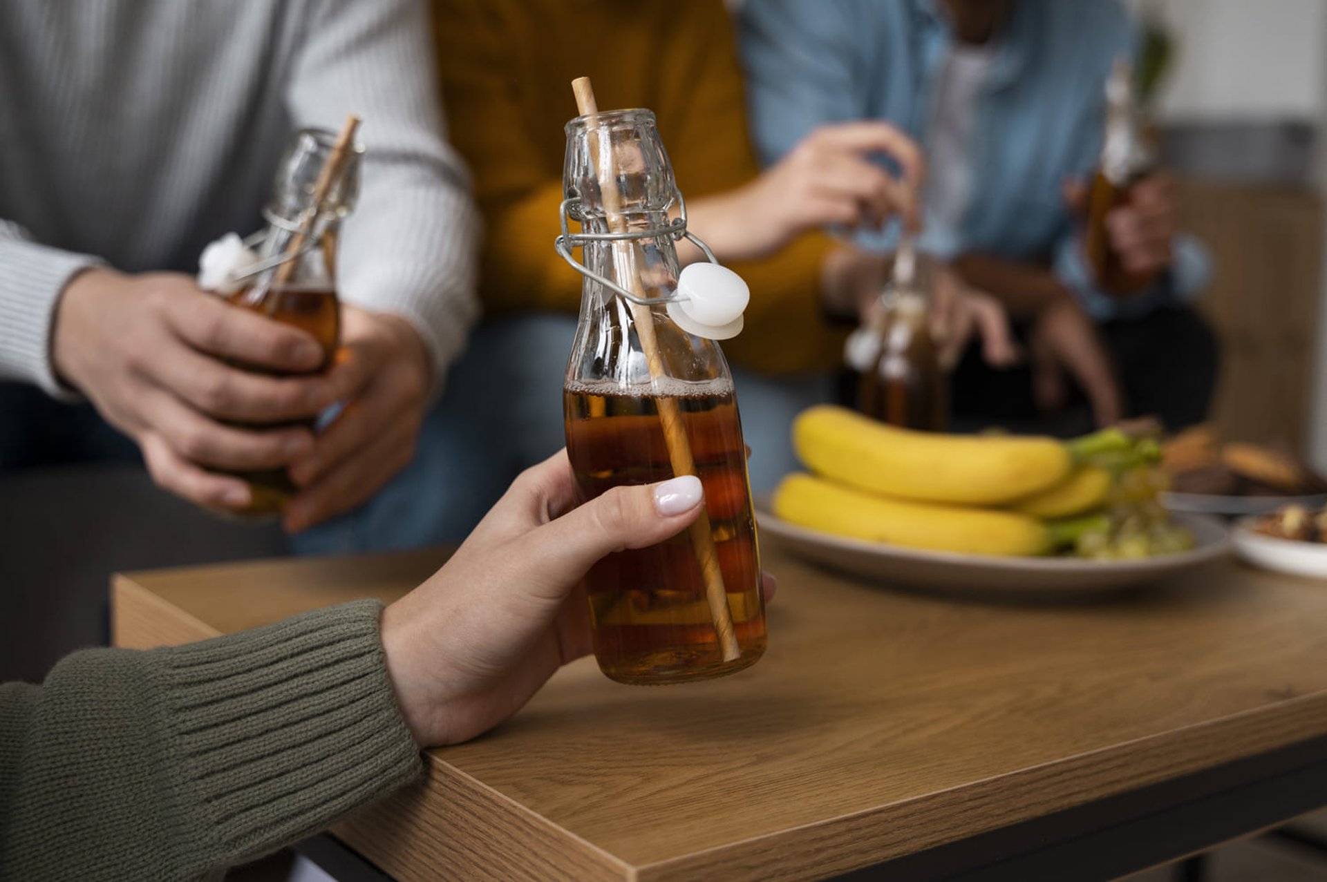 Un grupo de jovenes tomando kombucha en una reunión amistosa.