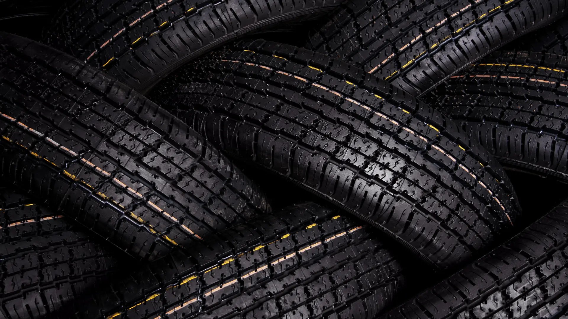 Pila de cubiertas nuevas de auto con líneas amarillas, fondo de neumáticos para venta en Jesús María.