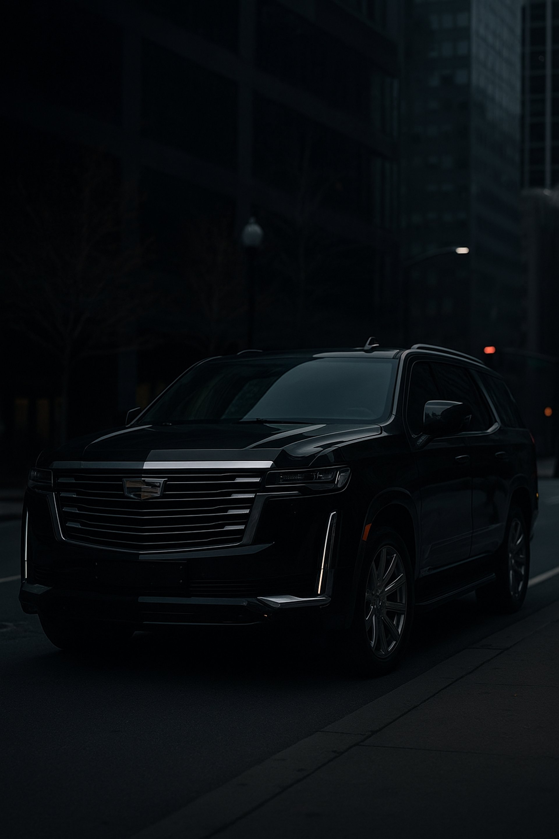 A black car driving down a street next to tall buildings