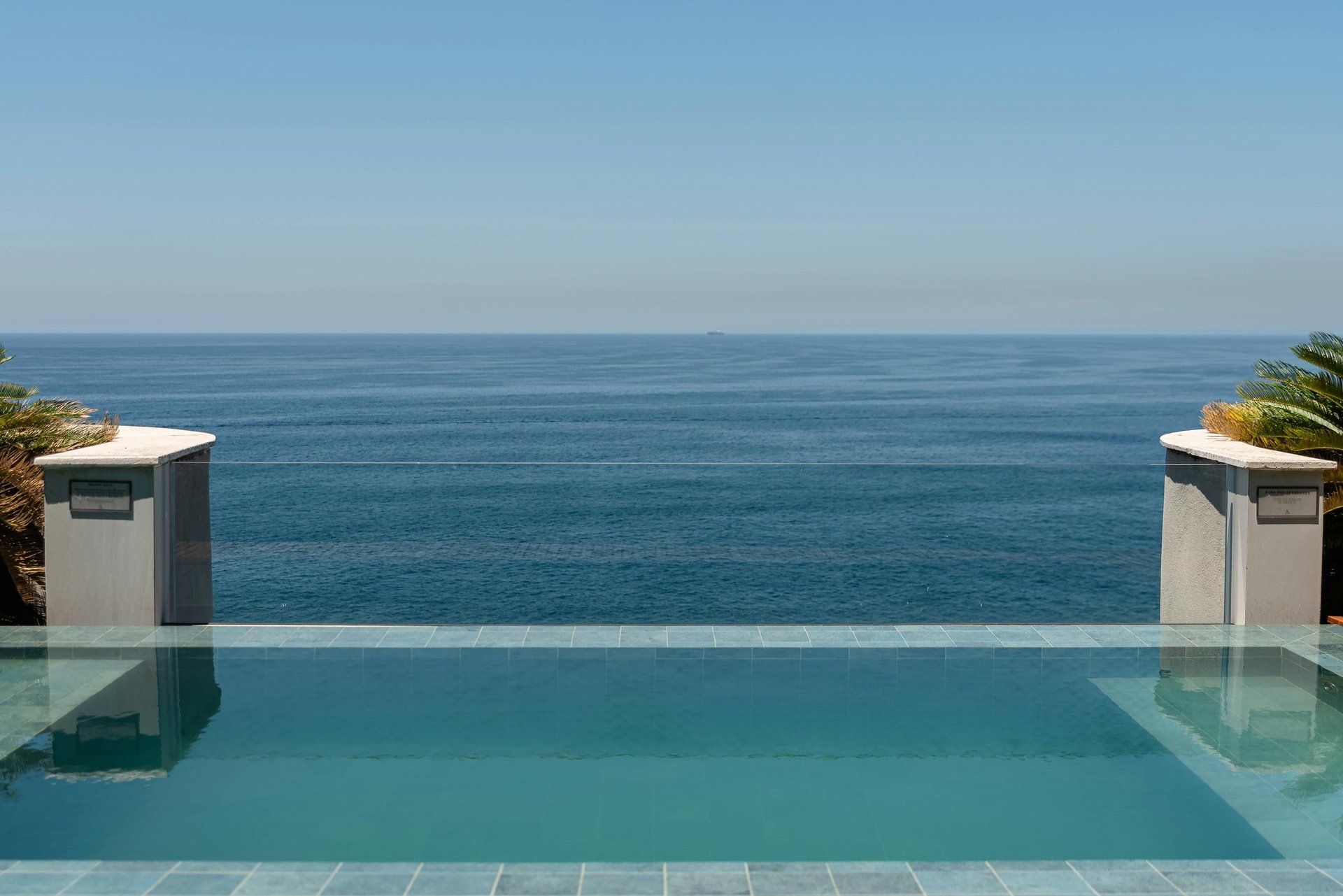 A bright blue swimming pool overlooks the vast ocean.