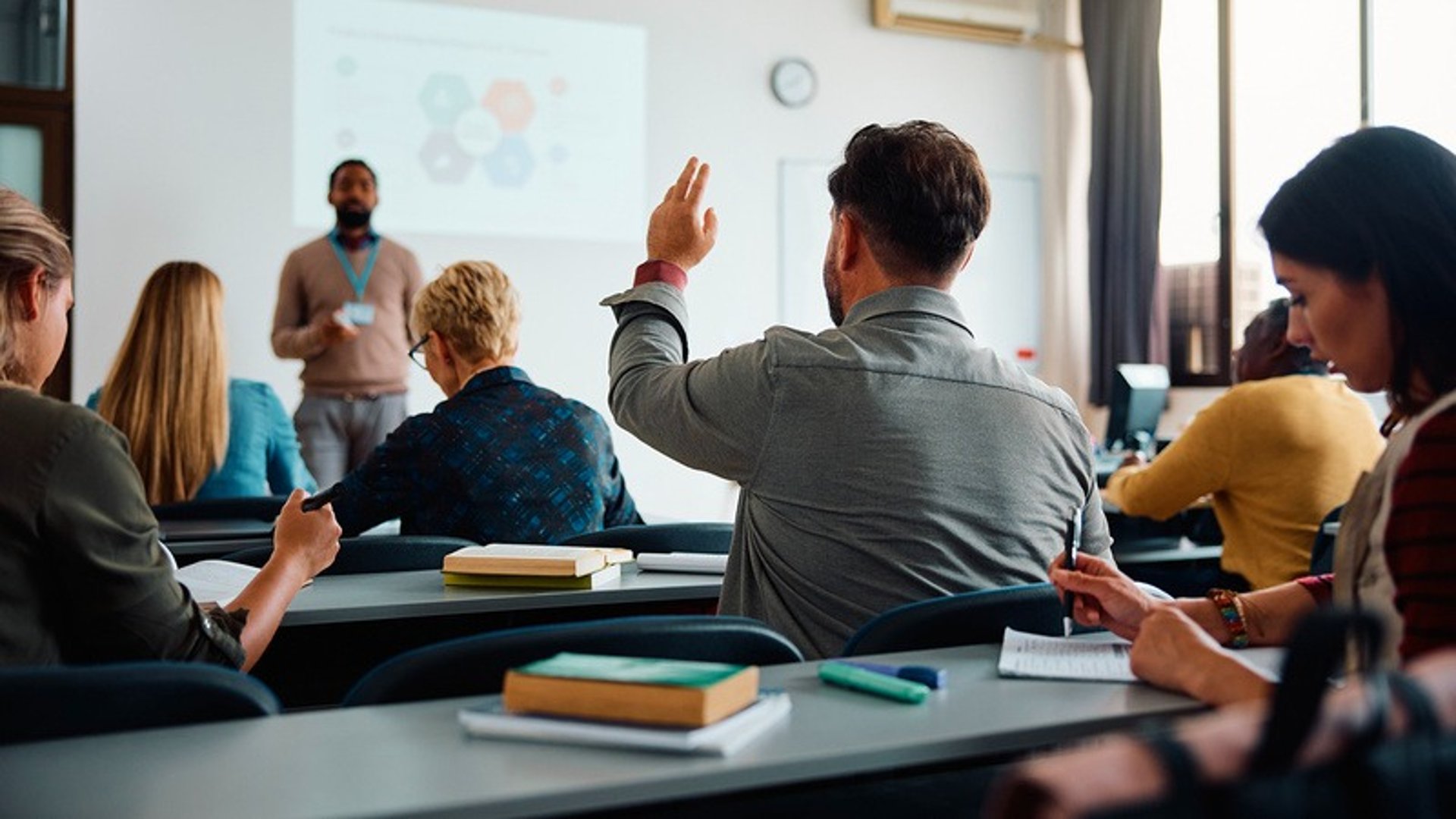 person holding pencil near laptop computer
