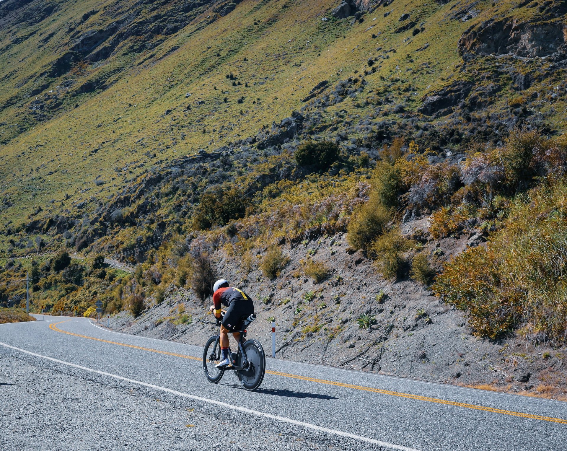 A person riding a bike on a road with mountains in the background