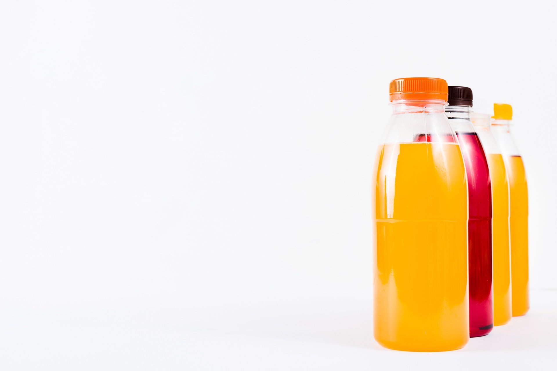 A row of bottles of juice sitting on top of a wooden table