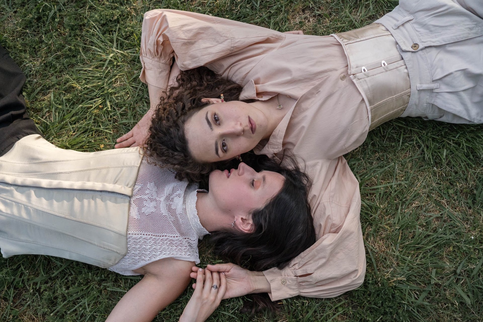"Pareja lesbiana vista desde arriba, abrazándose en el suelo, celebrando el amor en una boda gay."