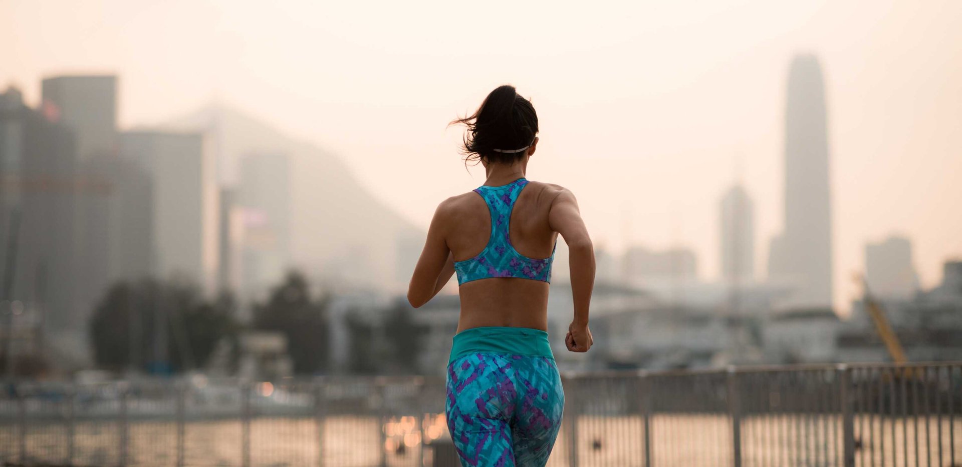 The back of a woman running, with the Hong Kong skyline in the background