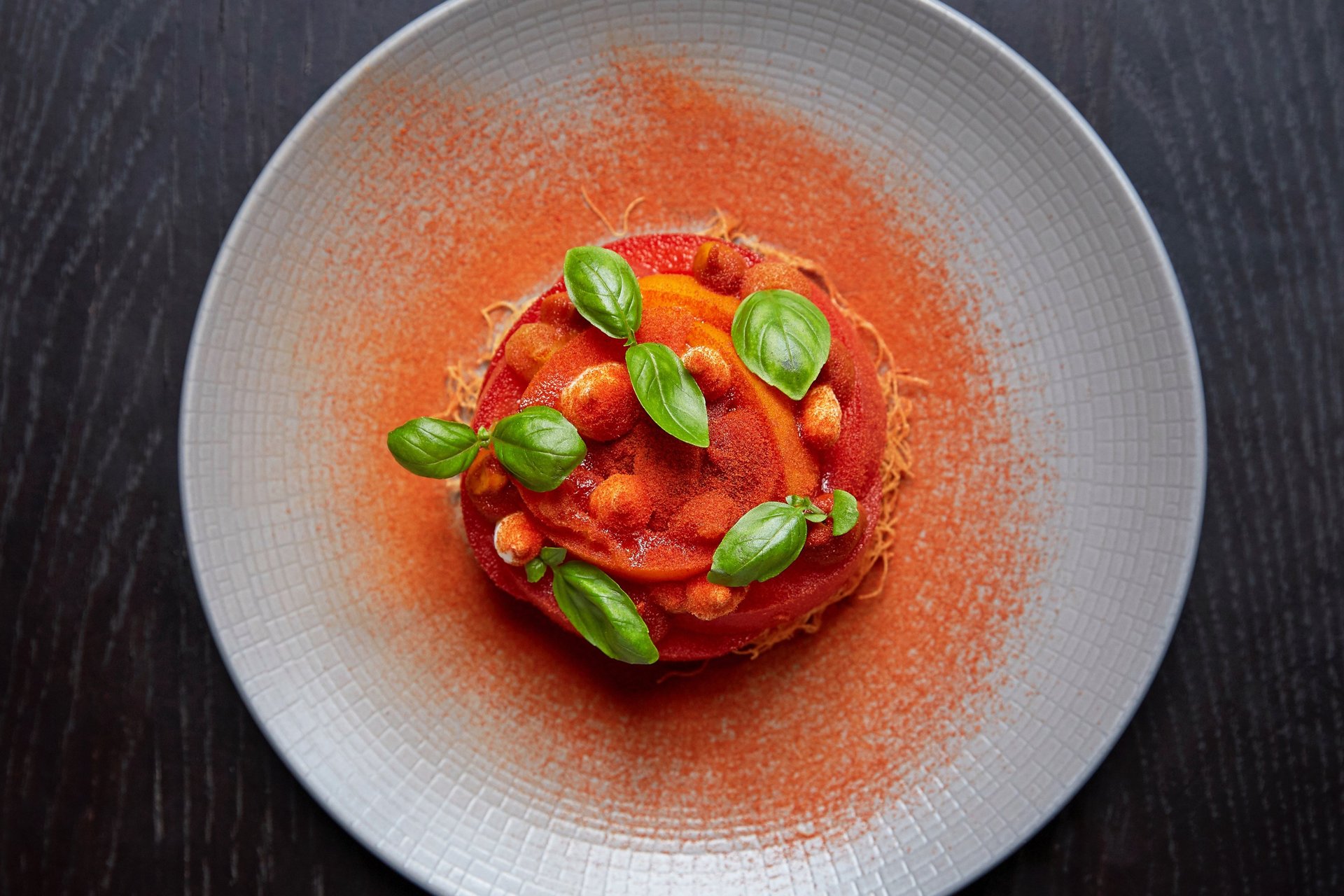 man in gray jacket and black backpack standing on green grass field near mountain during daytime