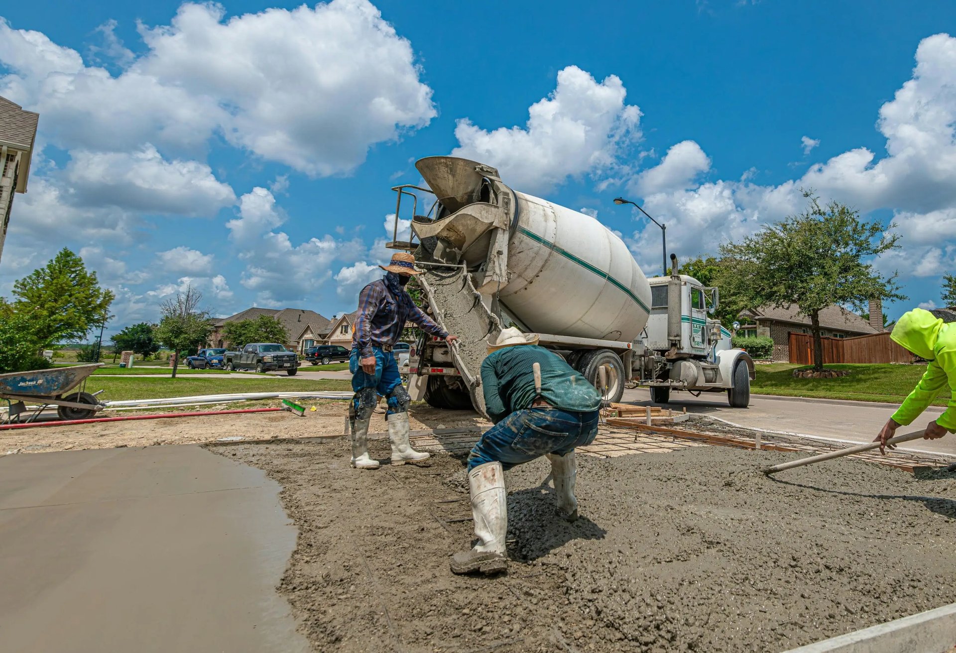 Men pouring fresh concrete for a driveway installation