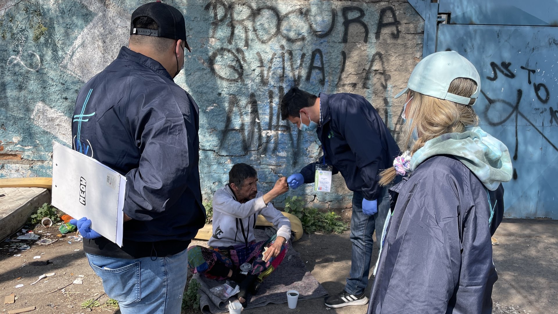 man giving food on man sitting on corner of wall