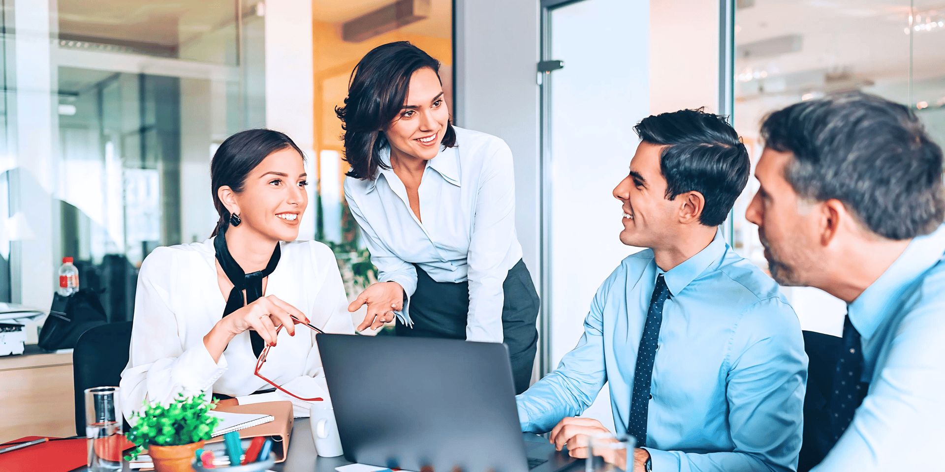Female sales leader engaging with her team of three in an office boardroom