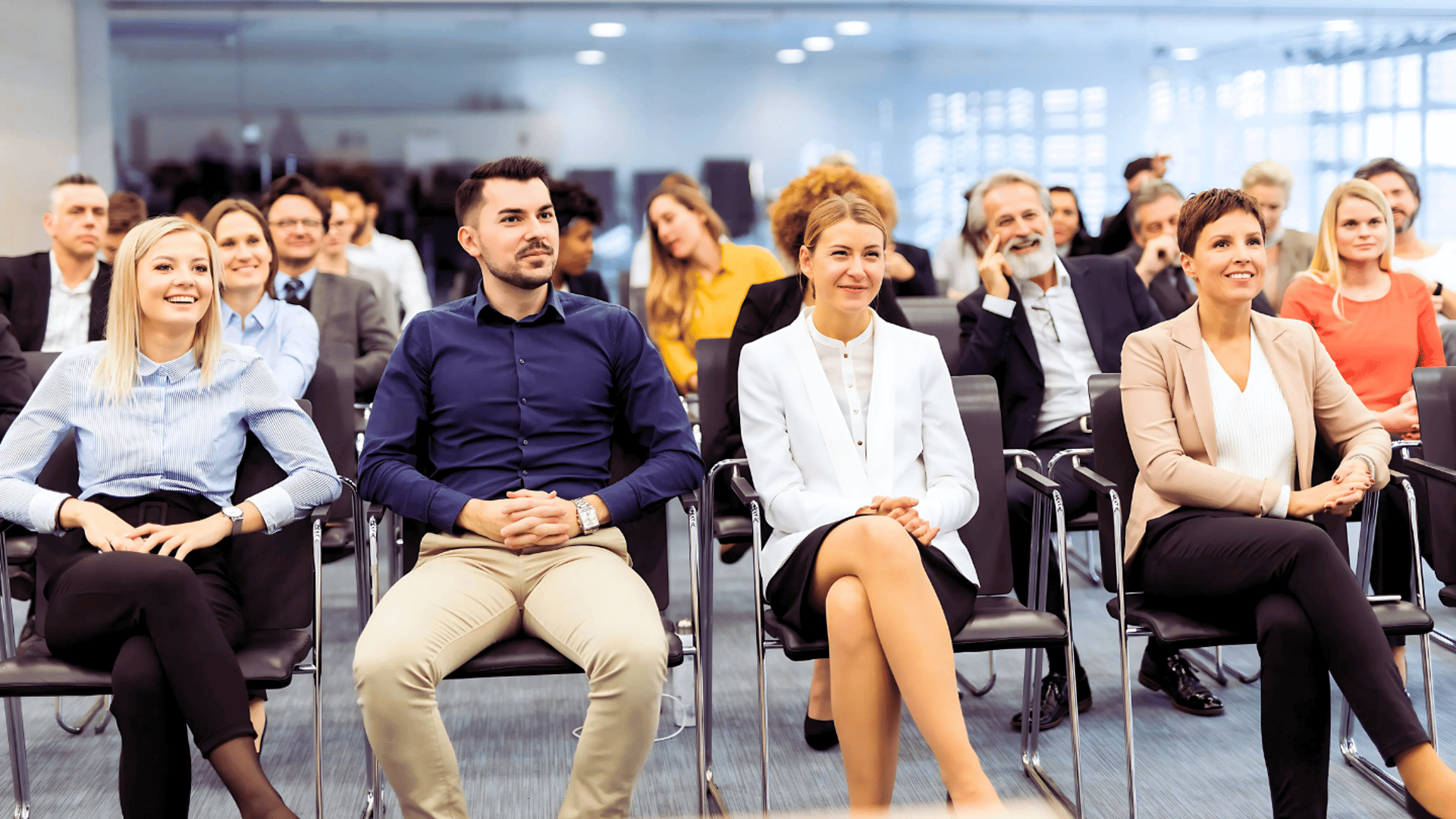 A group of leaders sits at a conference, appearing engaged with a keynote speaker who is offscreen.