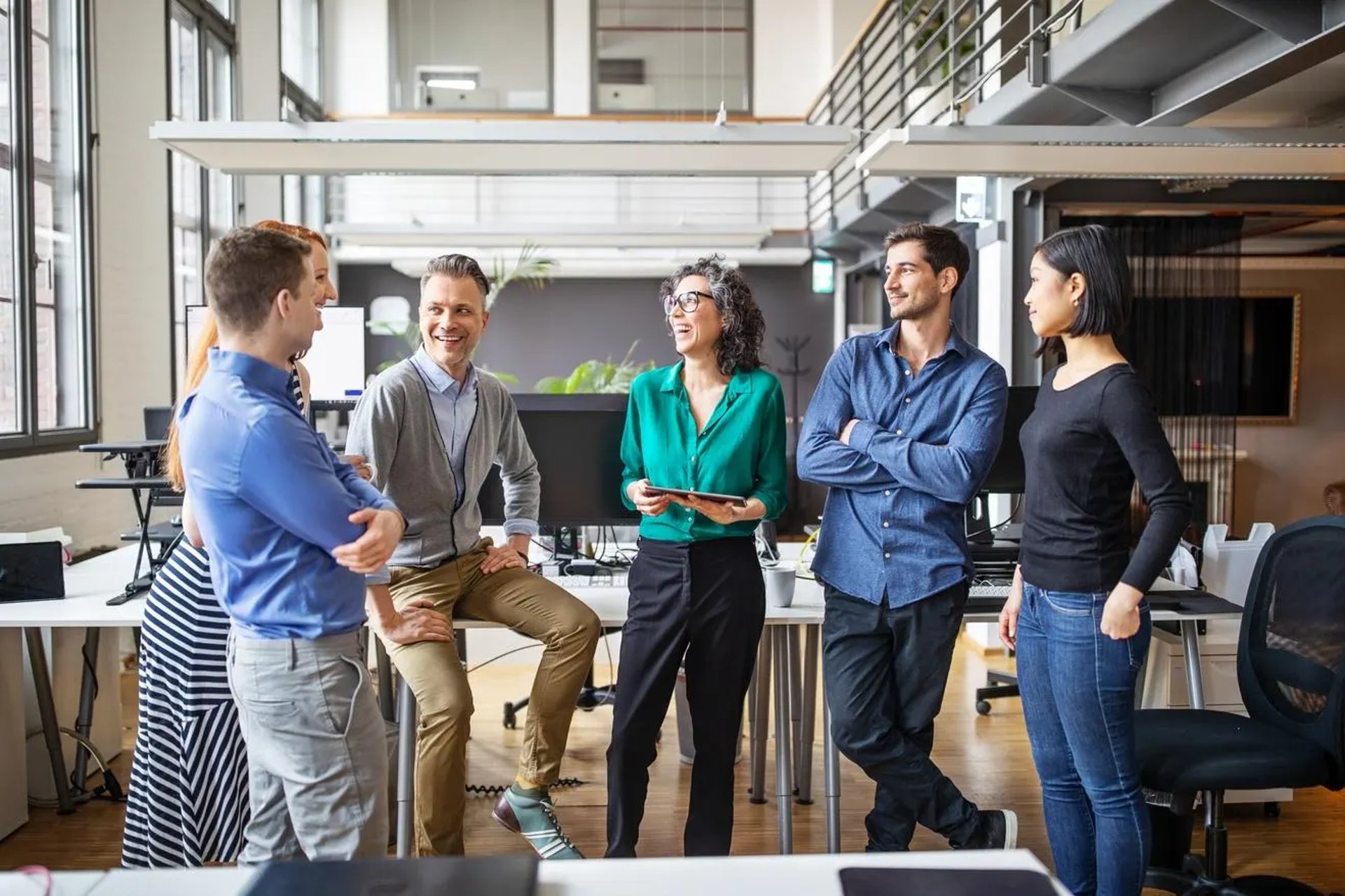 A group of leaders stands in a semicircle for a team meeting in the office.