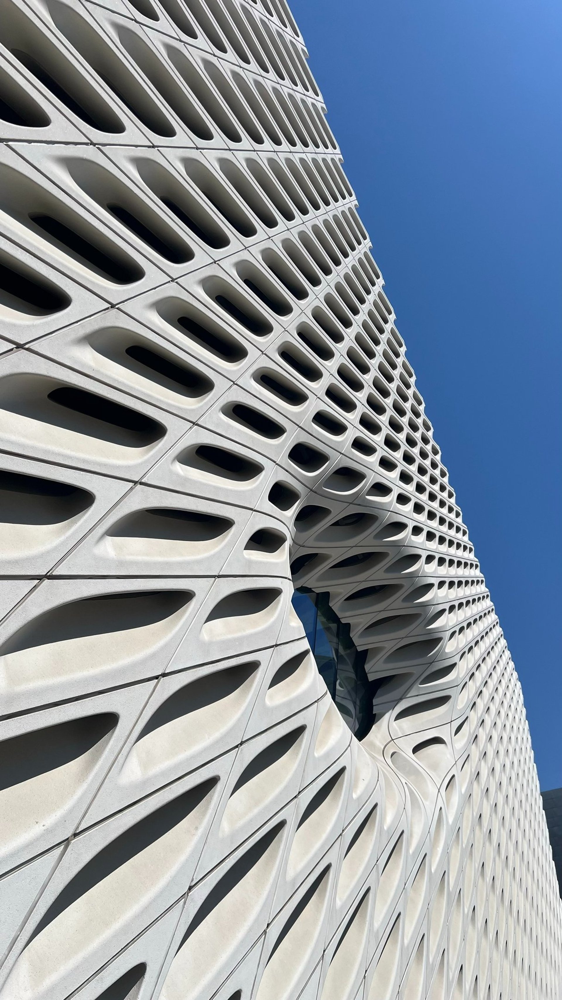 an abstract photo of a curved building with a blue sky in the background