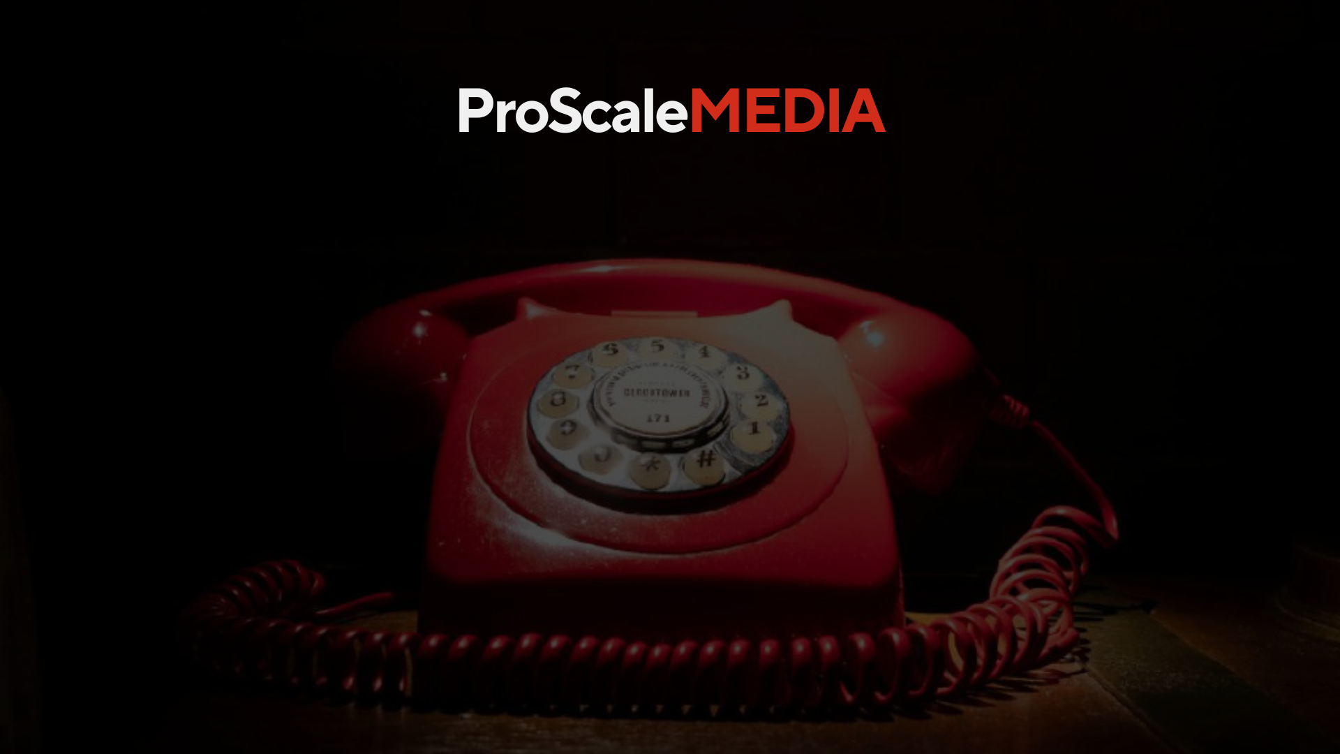 A red telephone sitting on top of a wooden table