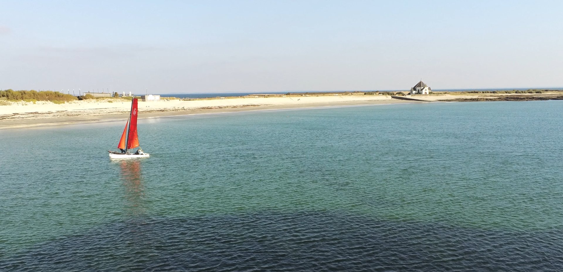 Plage de Penvins avec chapelle Notre-Dame-de-la-Côte et catamaran en mer, Camping La Grée Penvins, Morbihan