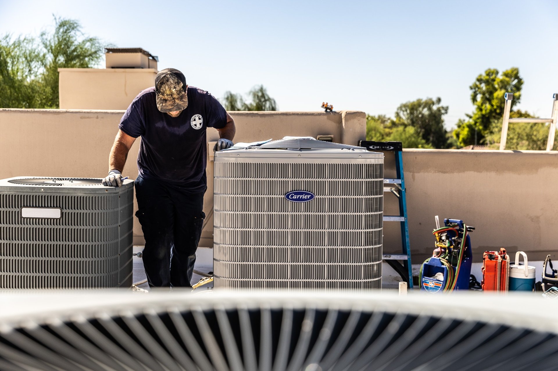 Hvac technician working on rooftop with carrier unit