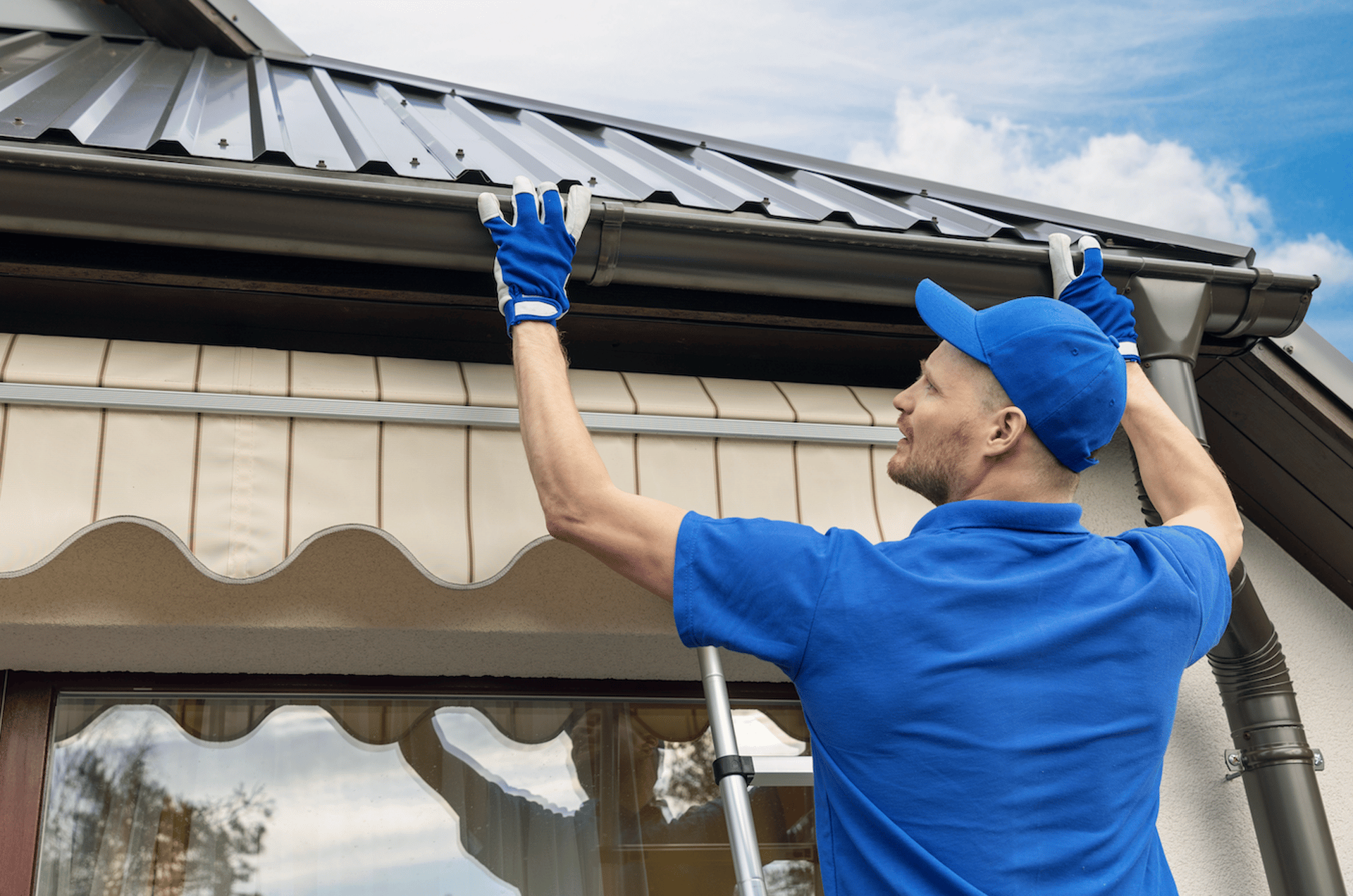Man cleans gutters on a two story house