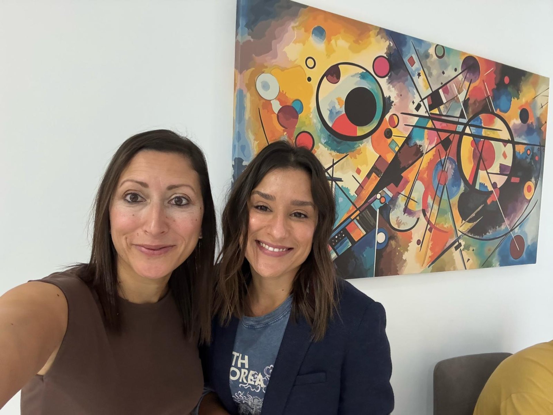 man in brown jacket sitting on concrete fence during daytime