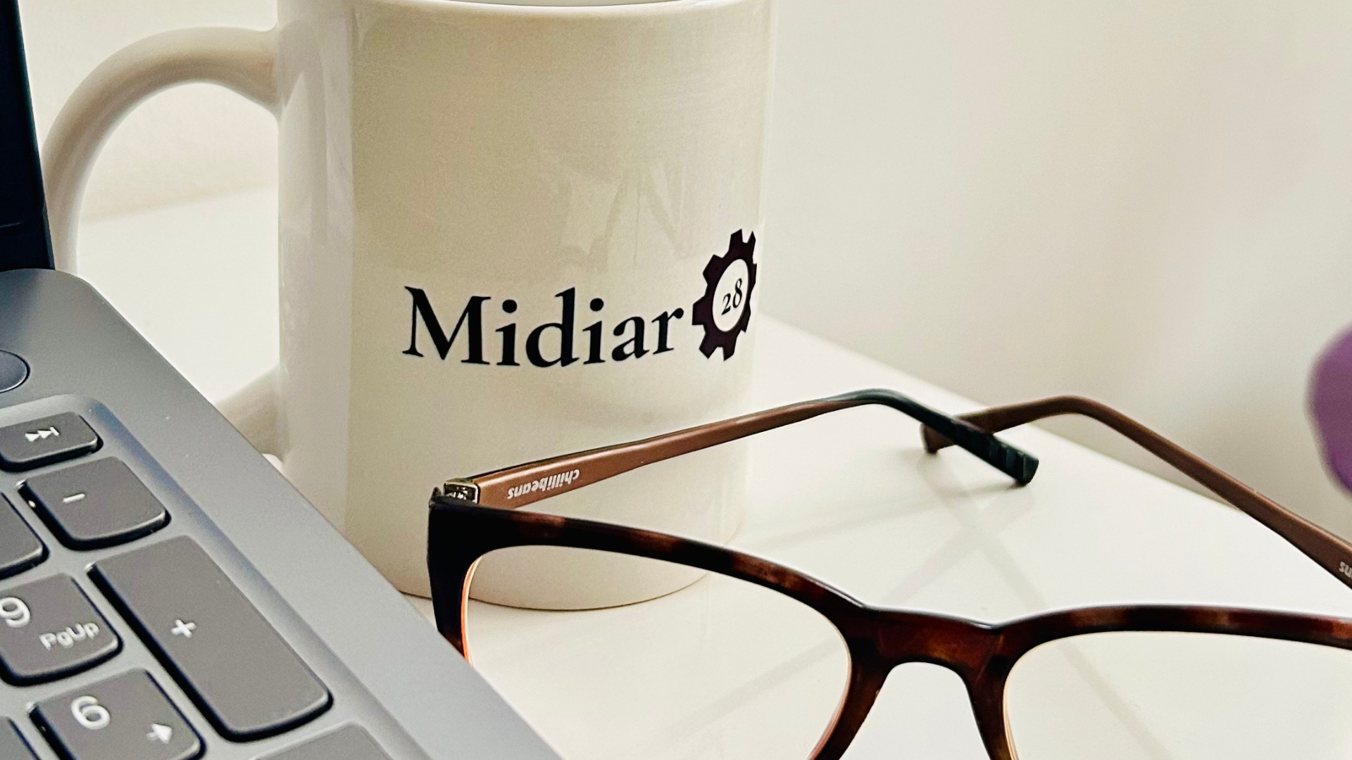 um-óculos-de-grau-proximo-a-uma-caneca-escrito-midiar-28-e-a-tela-de-um-computador