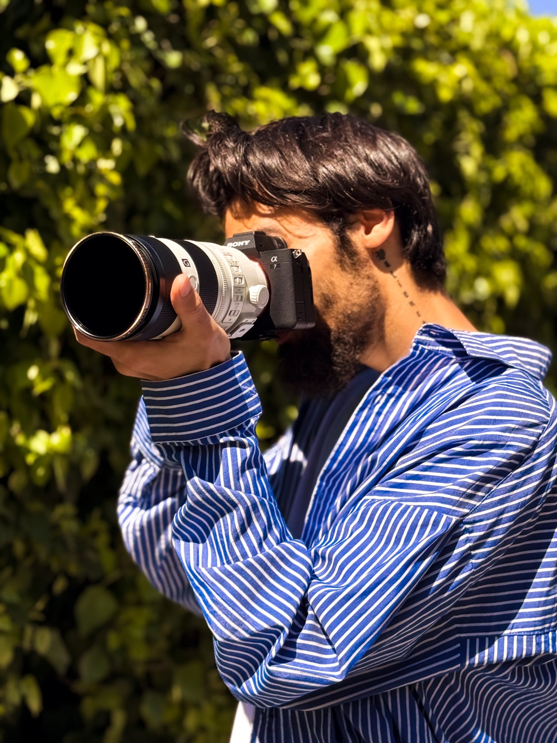 silhouette photo of man in front of DSLR camera with tripod under leafless tree