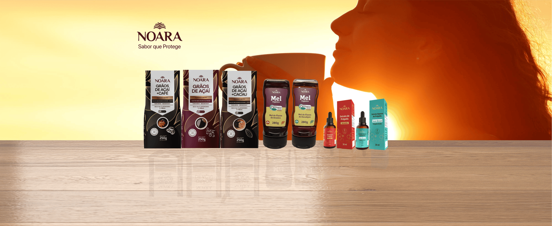 Mulher saboreando uma xícara de Café de Açaí Noara ao nascer do sol, com embalagens de grãos de açaí torrado e moído Noara