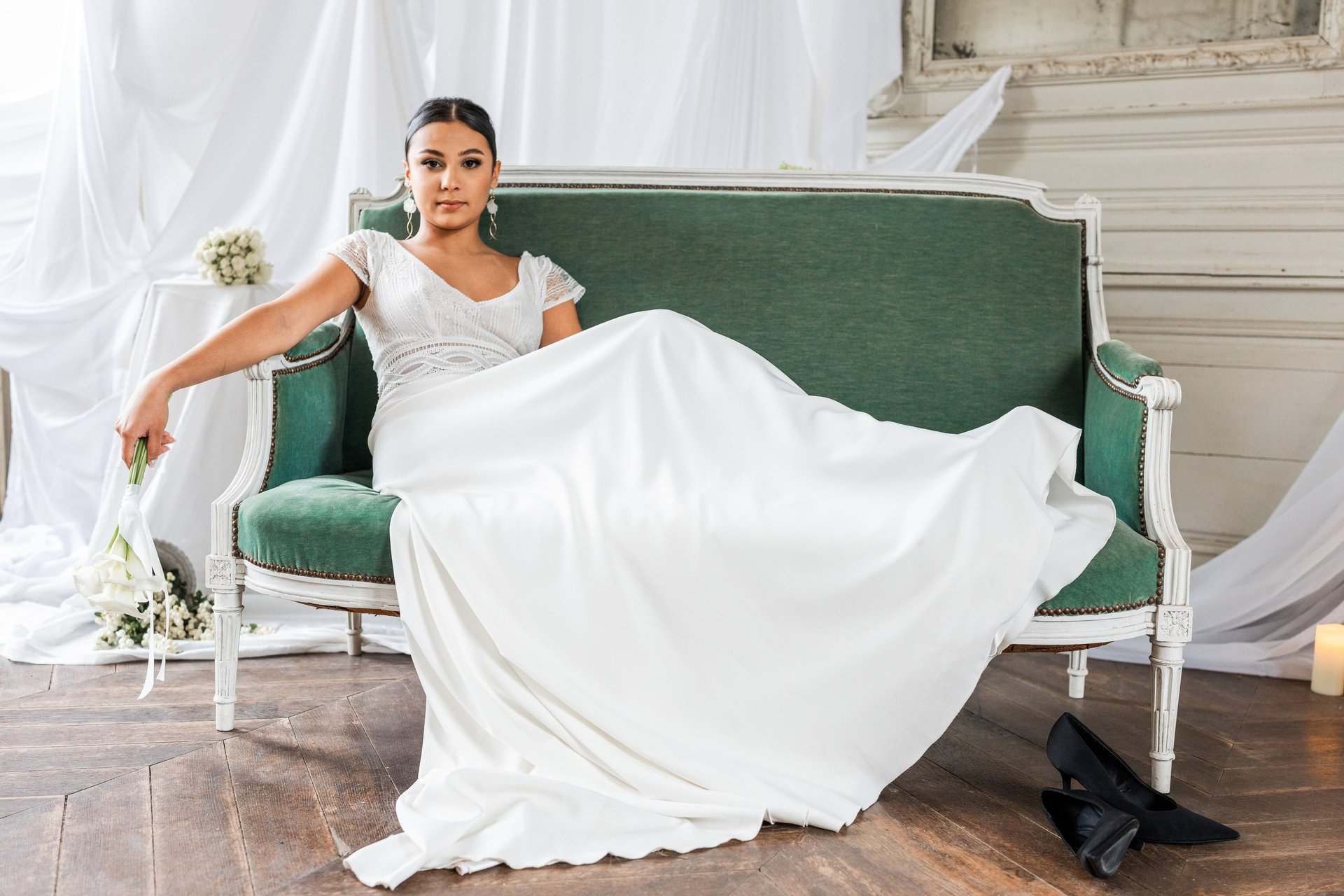 Une femme en robe de mariée allonfée sur un canapé un bouquet de fleurs à la main