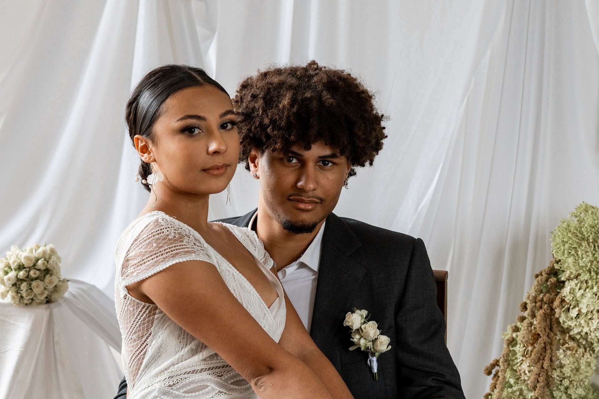 Un couple en tenue de mariés regardant la caméra