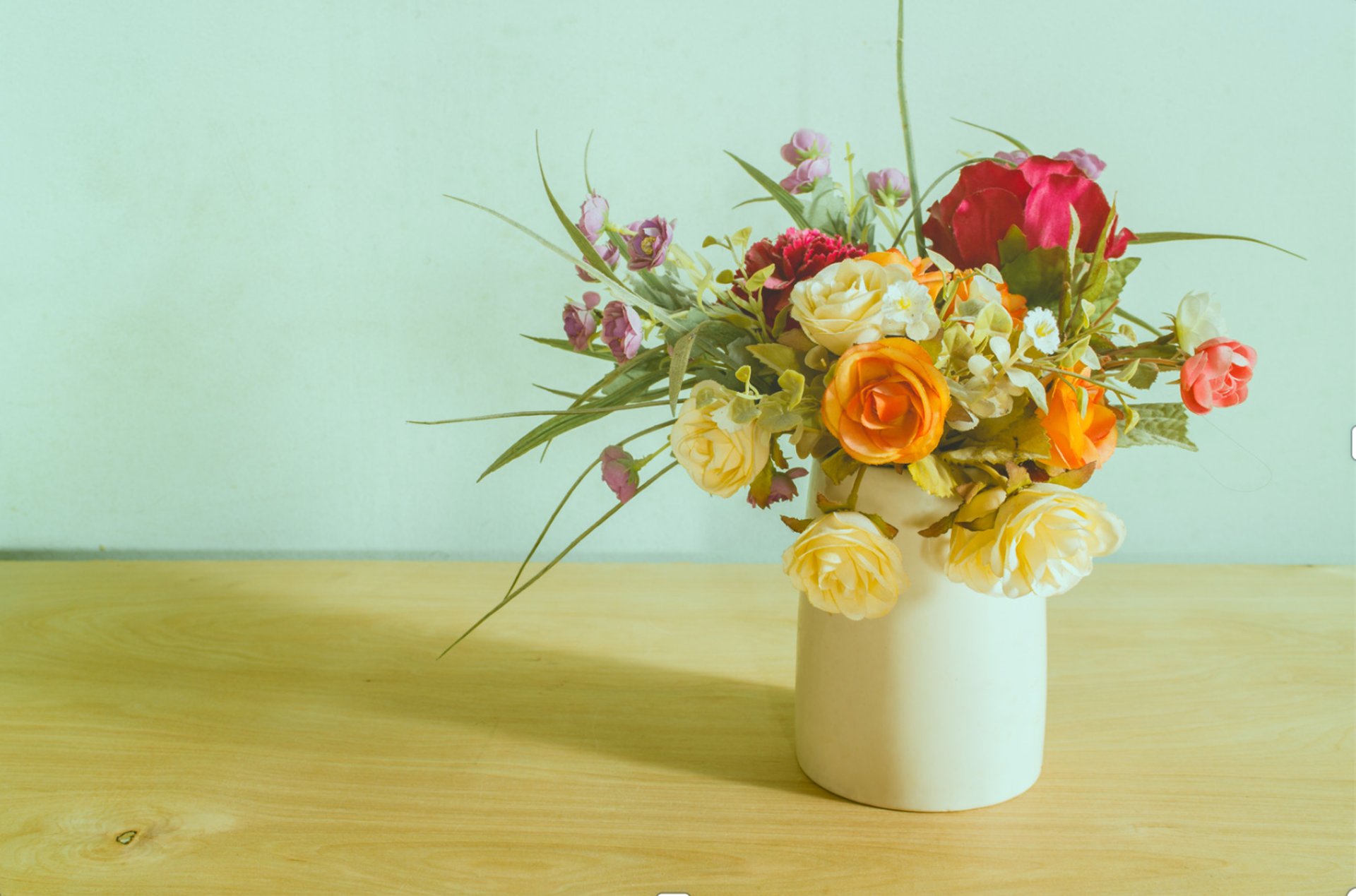 a vase filled with lots of flowers on top of a wooden table
