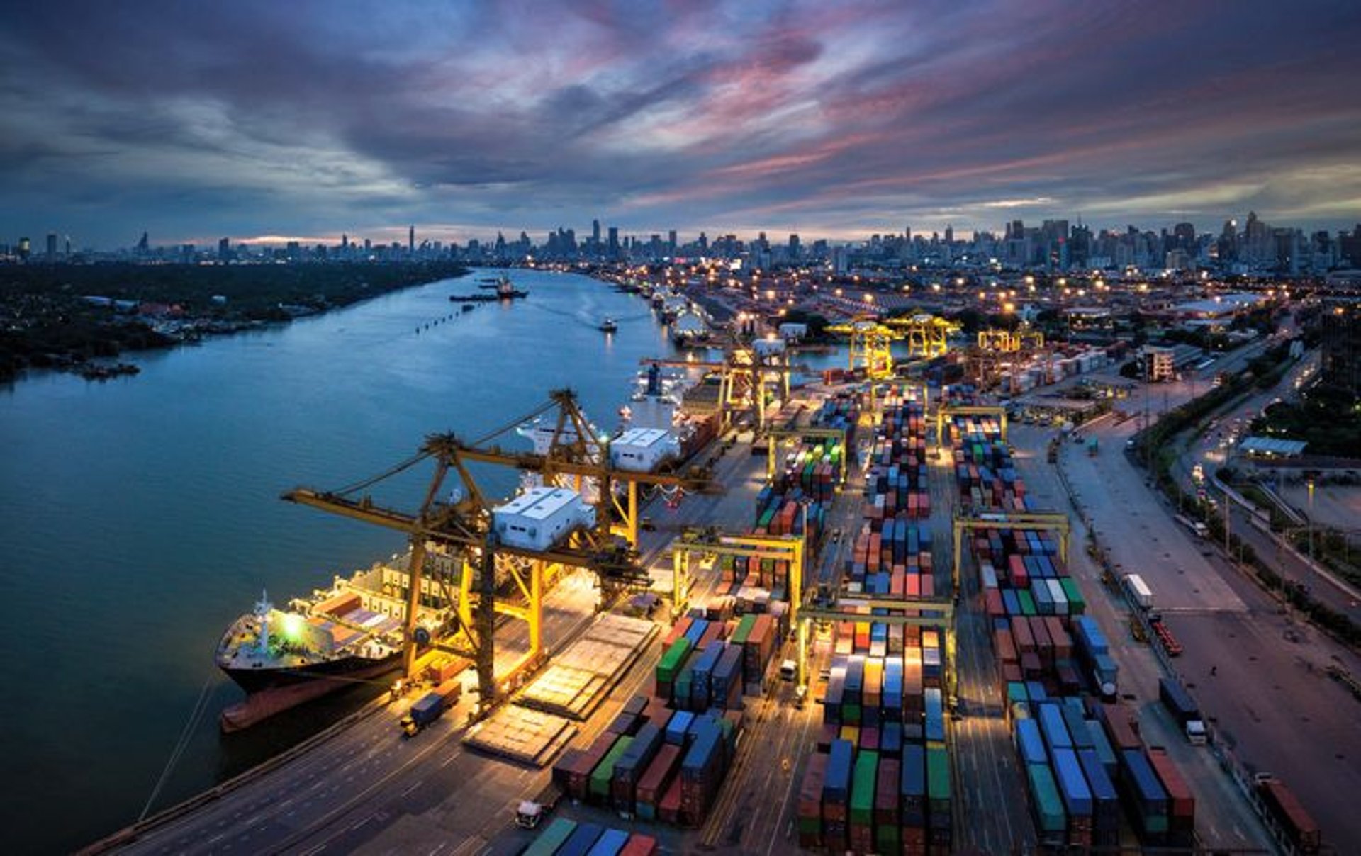 A cargo ship being loaded by a massive crane.