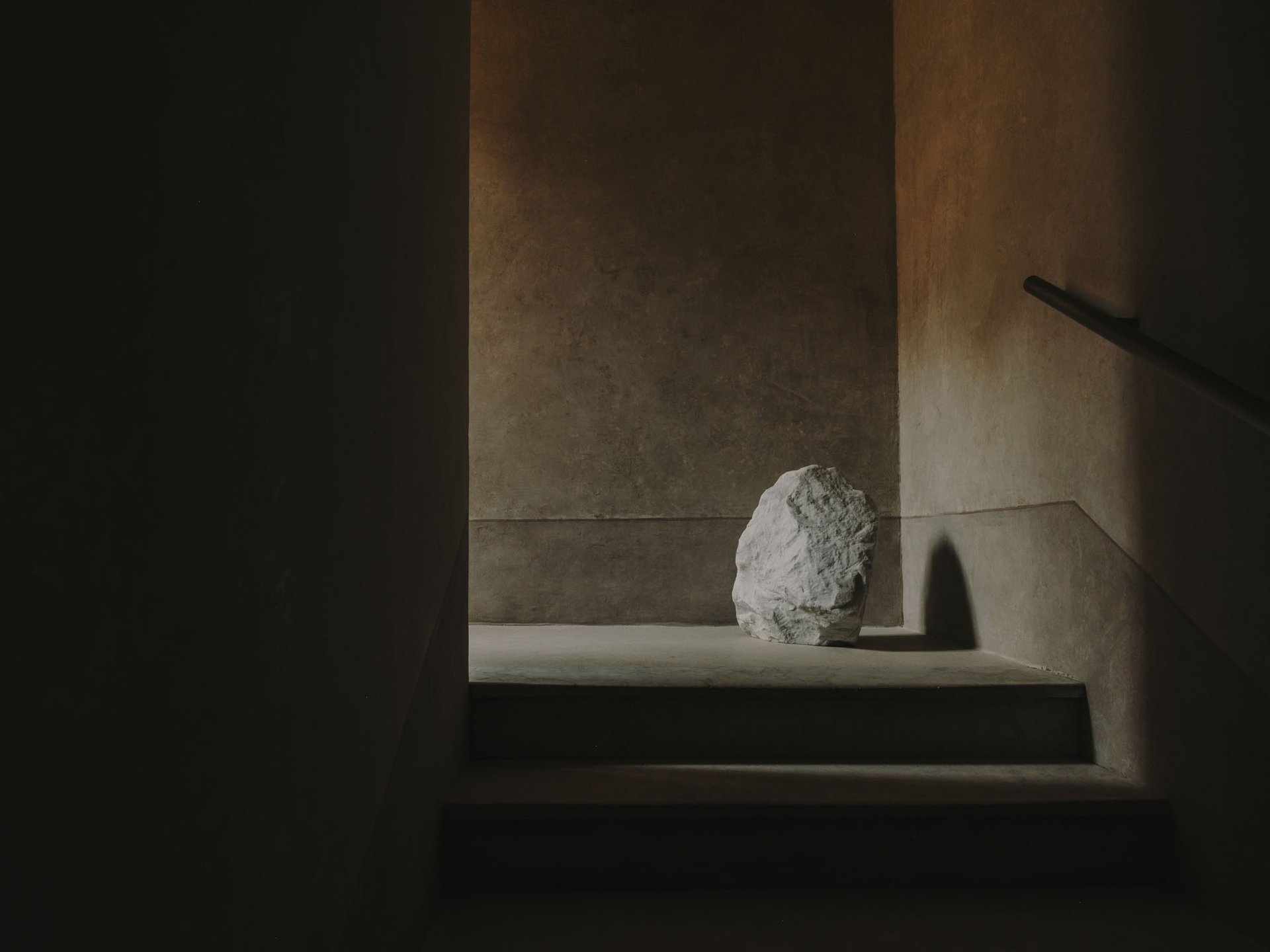 Composición minimalista con piedra y luz en escalera evocando contacto desde lo estético