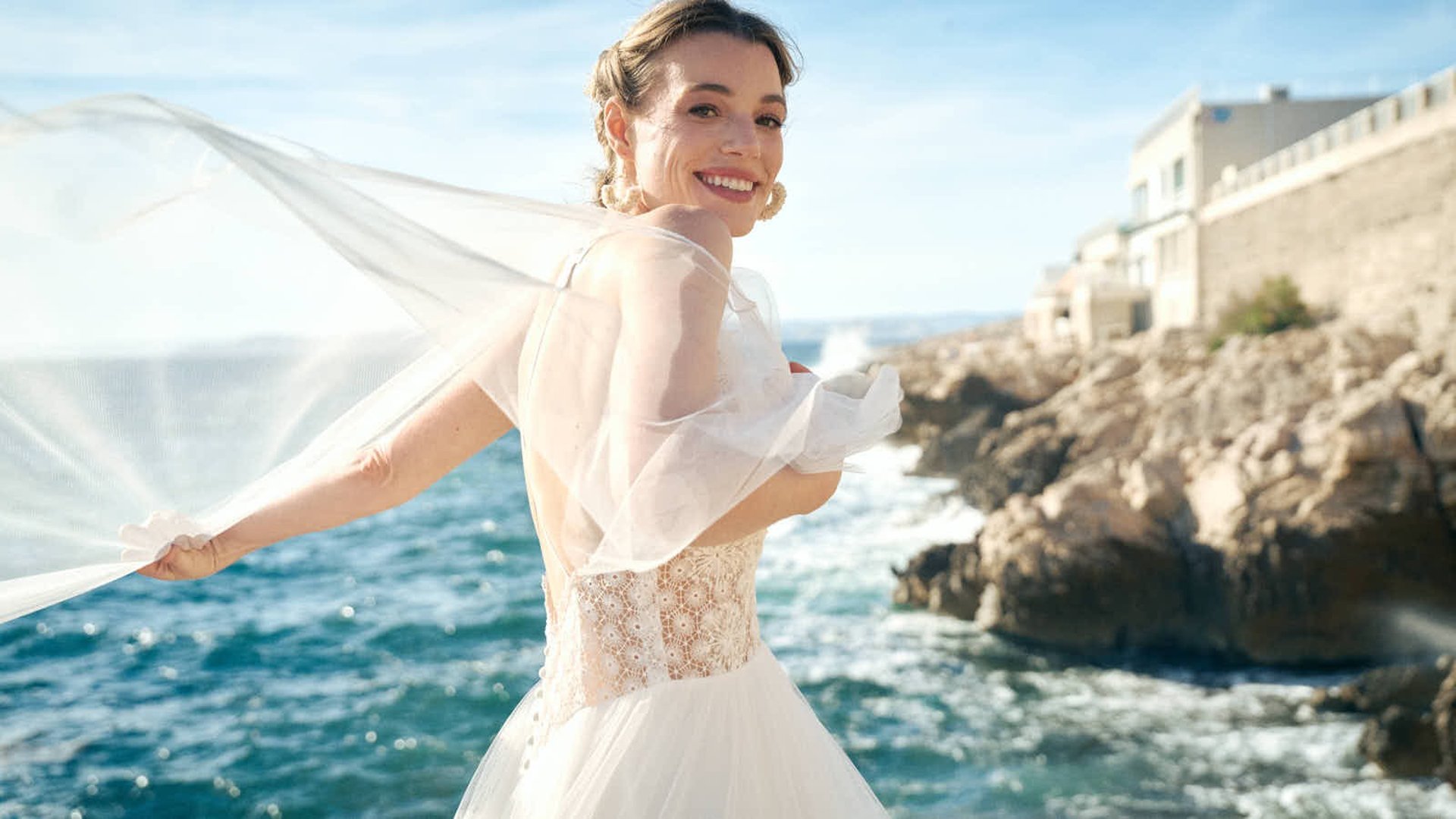 photo d'une mariée aux Goudes avec son voile qui vole au vent, sourire sincère