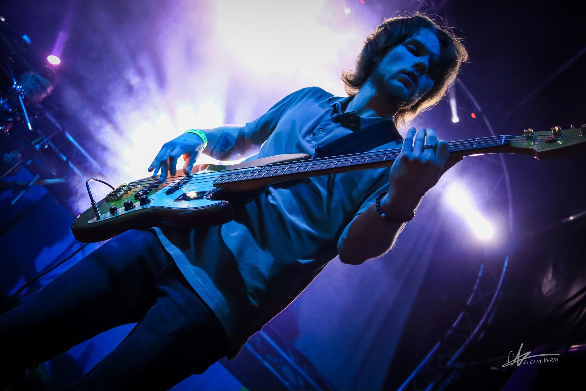 Thomas jouant de la basse avec energie lors du festival du petit wood de sémeries sous le feu des projecteurs 