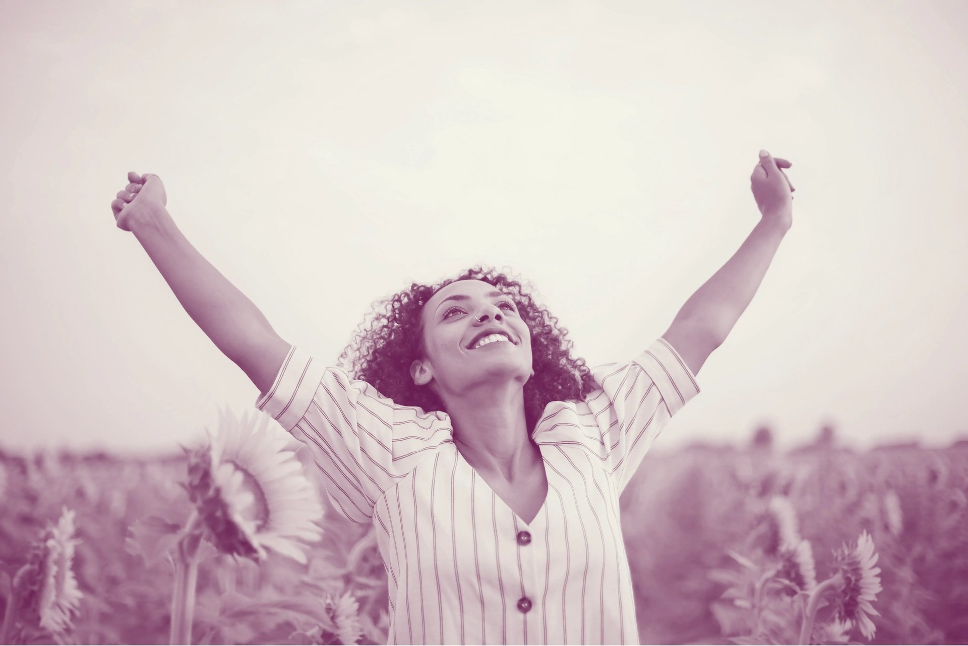 Woman raising her arms and standing on Sunflower Field