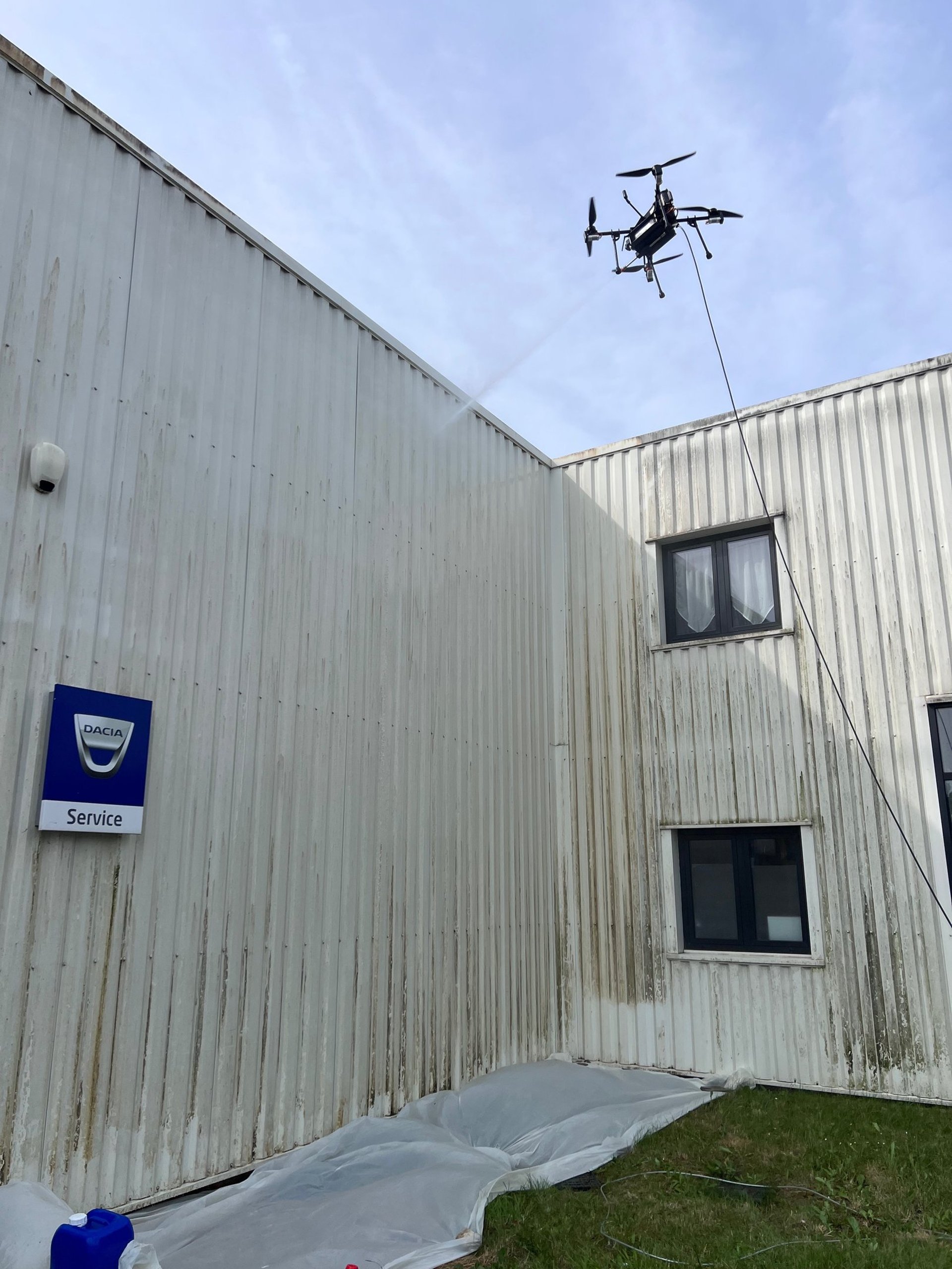 un drone monta qui pulvérise sur une façade