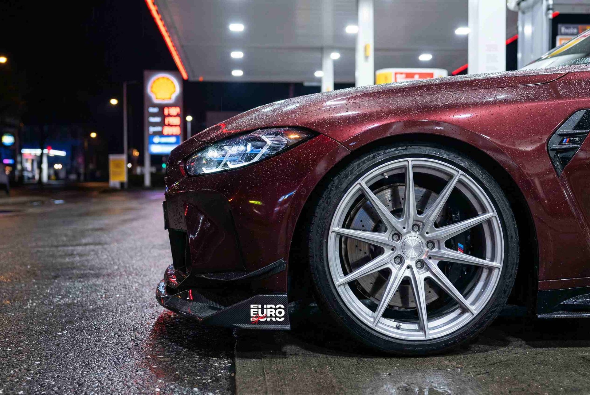 red BMW vehicle parked at the road near the blue gate