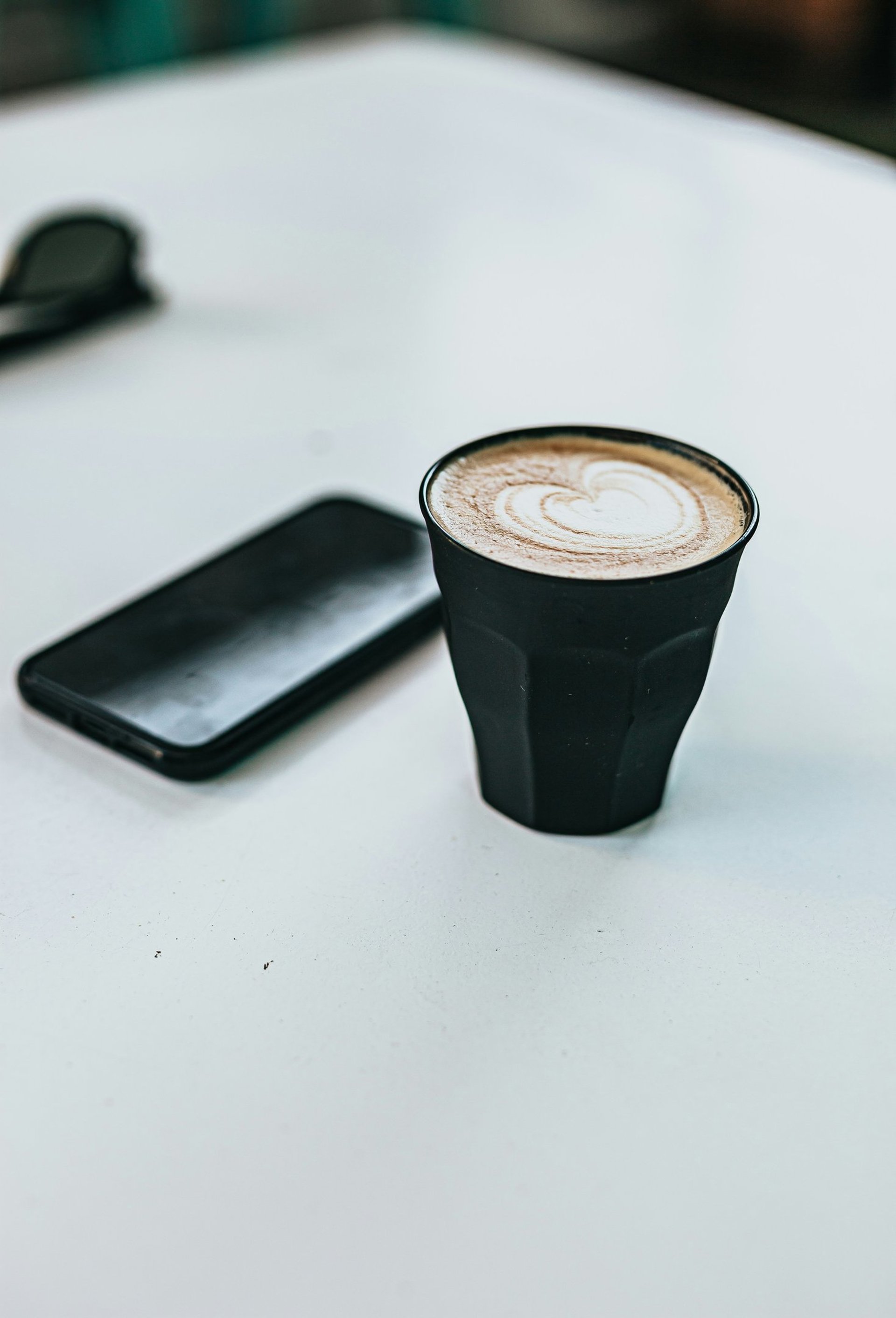 black and white coffee cup beside black iphone 5