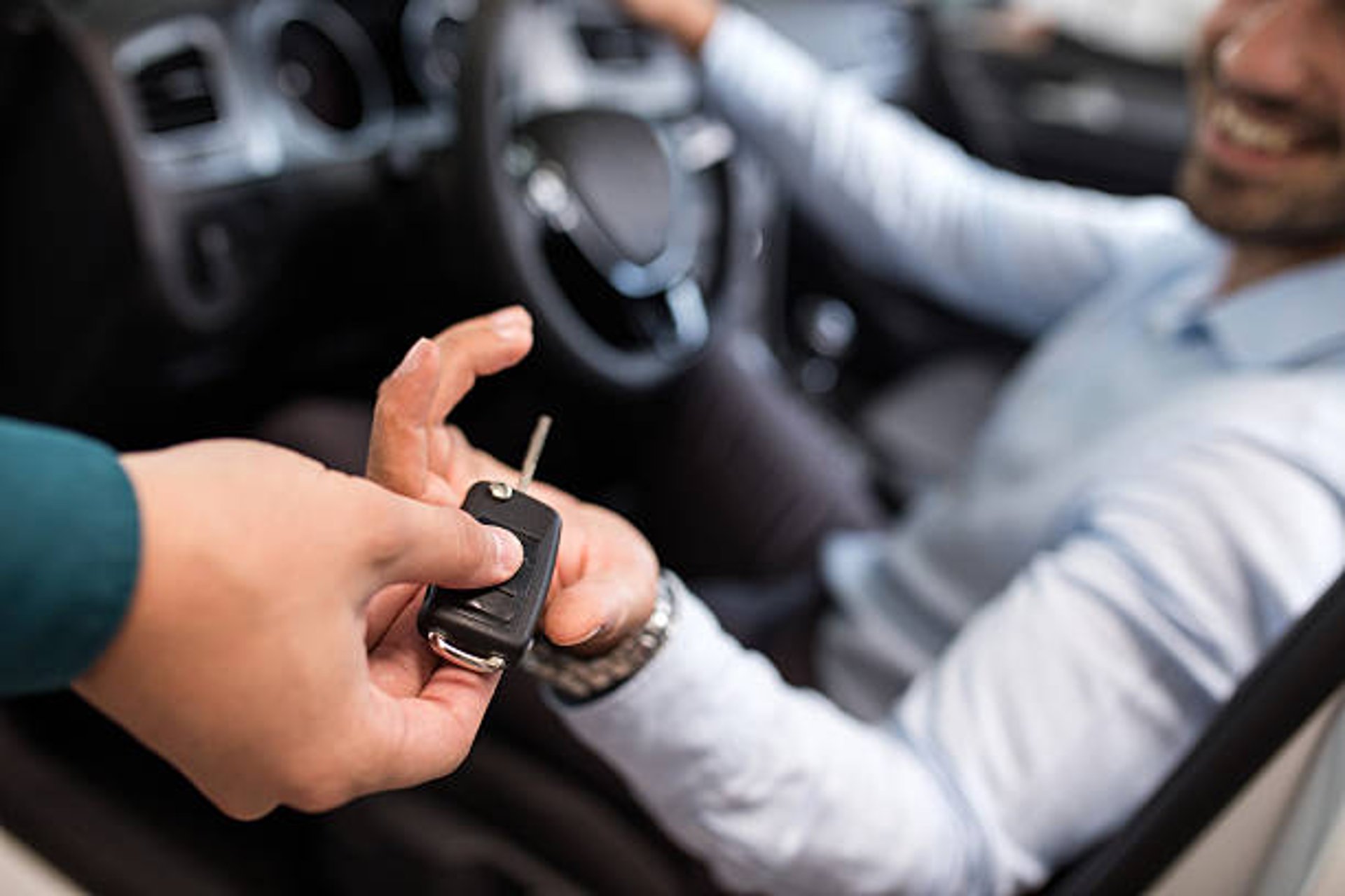 a person holding a car key next to a silver car