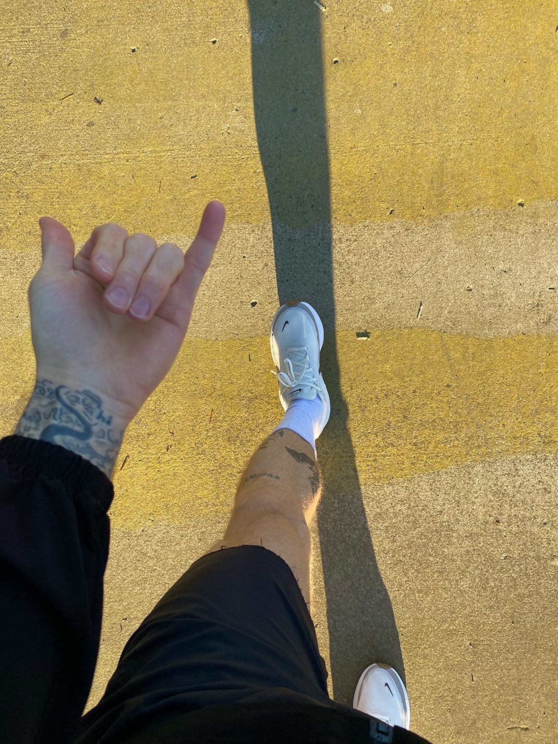 man in white shirt and blue shorts running on brown ground between green grass during daytime