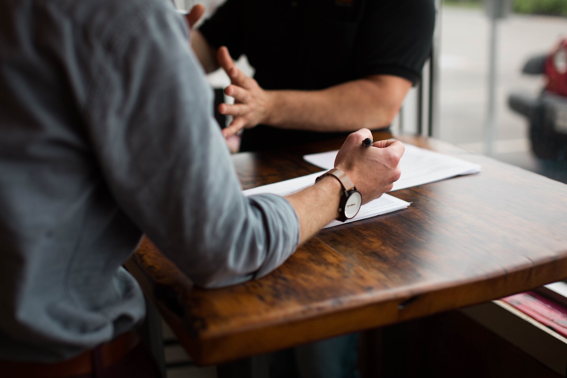 people sitting on chair in front of table while holding pens during daytime