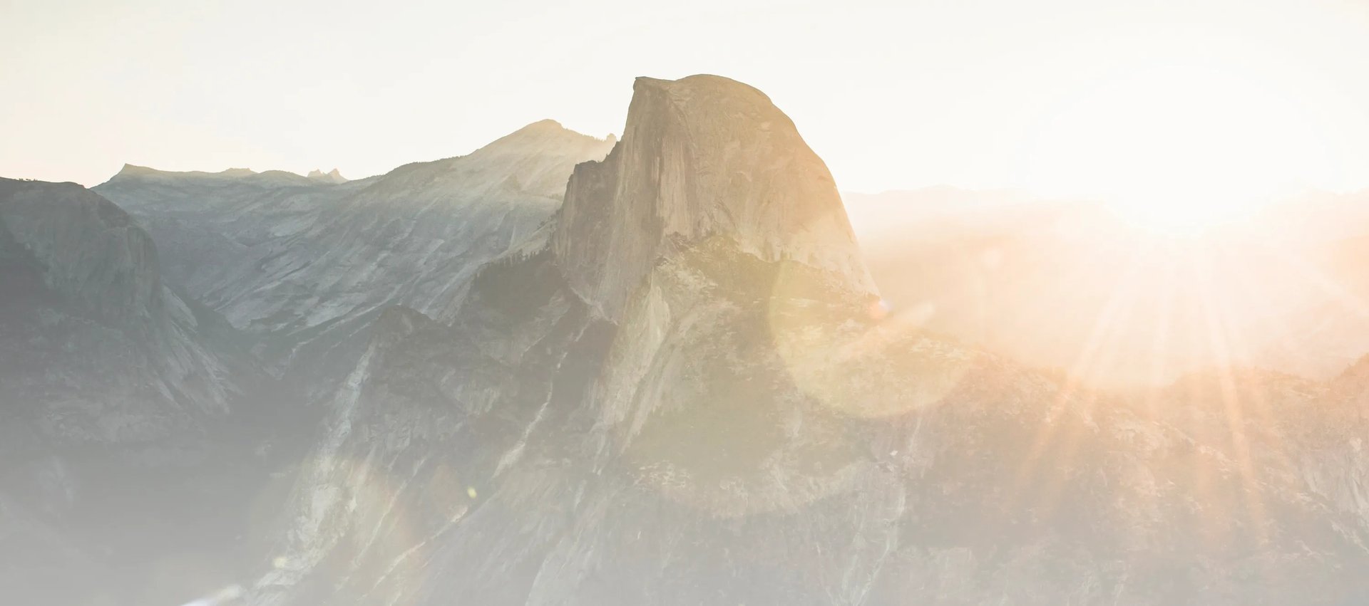 Montagne avec un col au milieu et un soleil éblouissant à droite