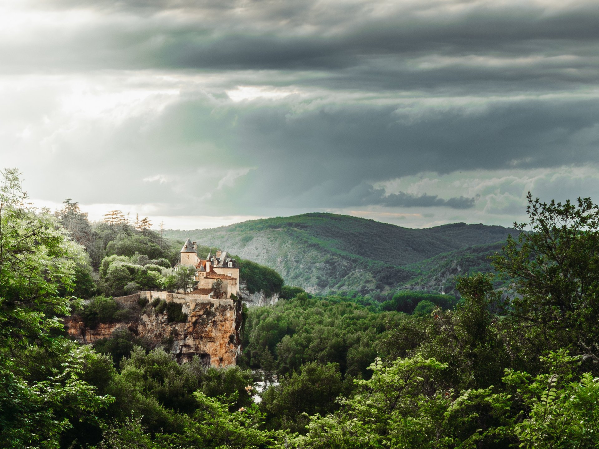 asphalt road beside of green trees in front of mountain covered of snow during daytime