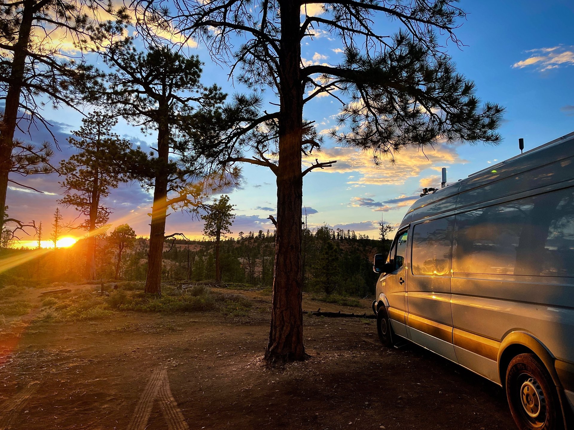 A custom built van at sunset in the midst of pine trees in a free camping area just outside of Bryce Canyon National Park. 