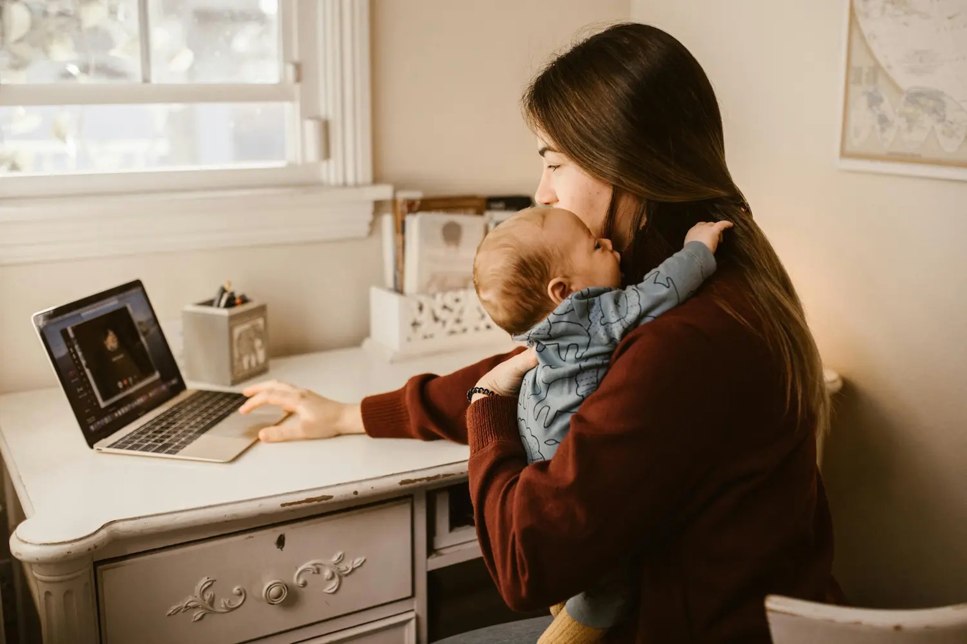 a woman sitting at a table with a child using a laptop