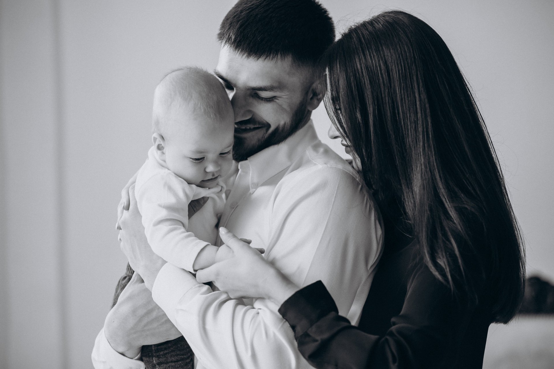 woman holding baby beside man smiling