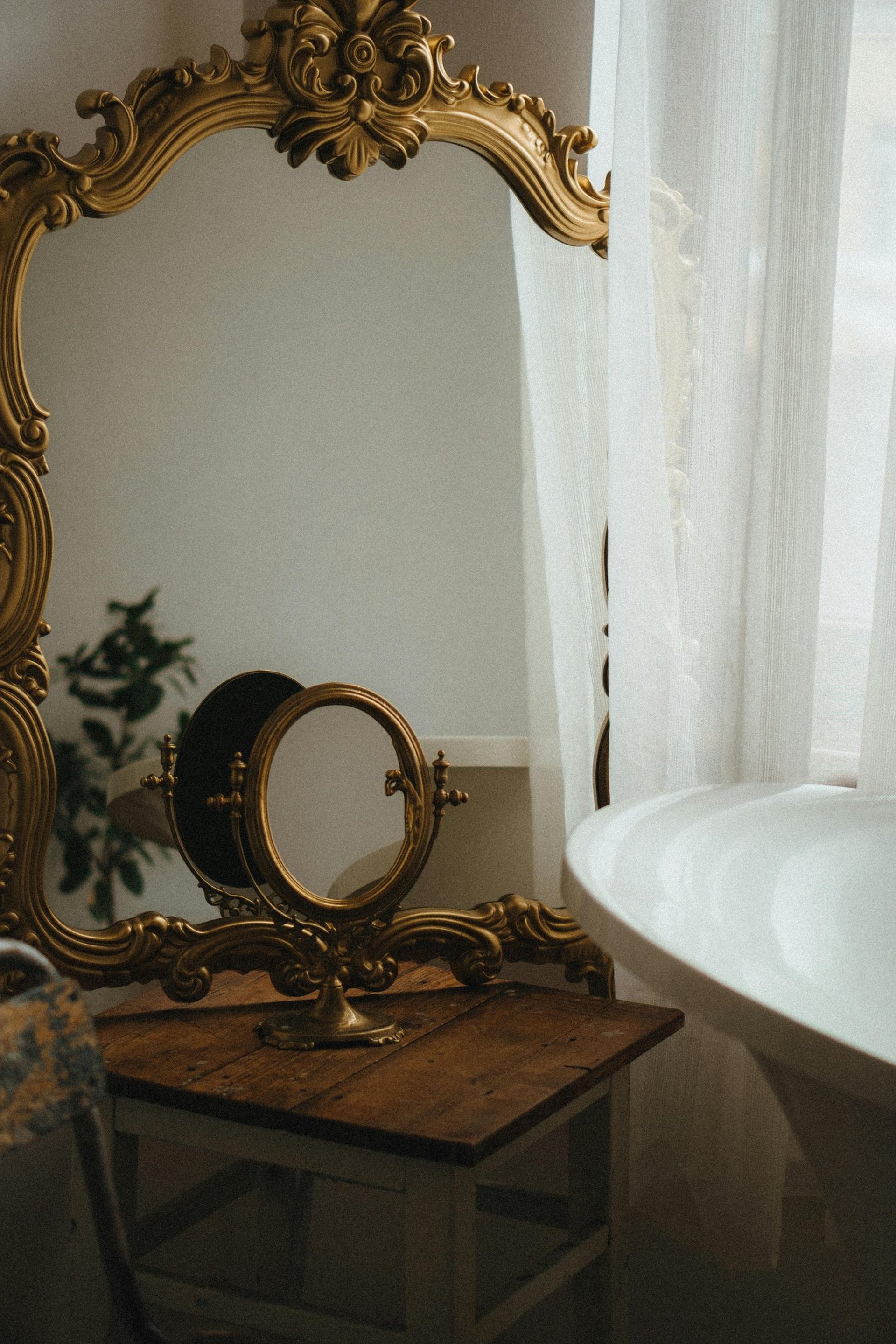 Miroir ancien à cadre doré sculpté dans une ambiance tamisée.
