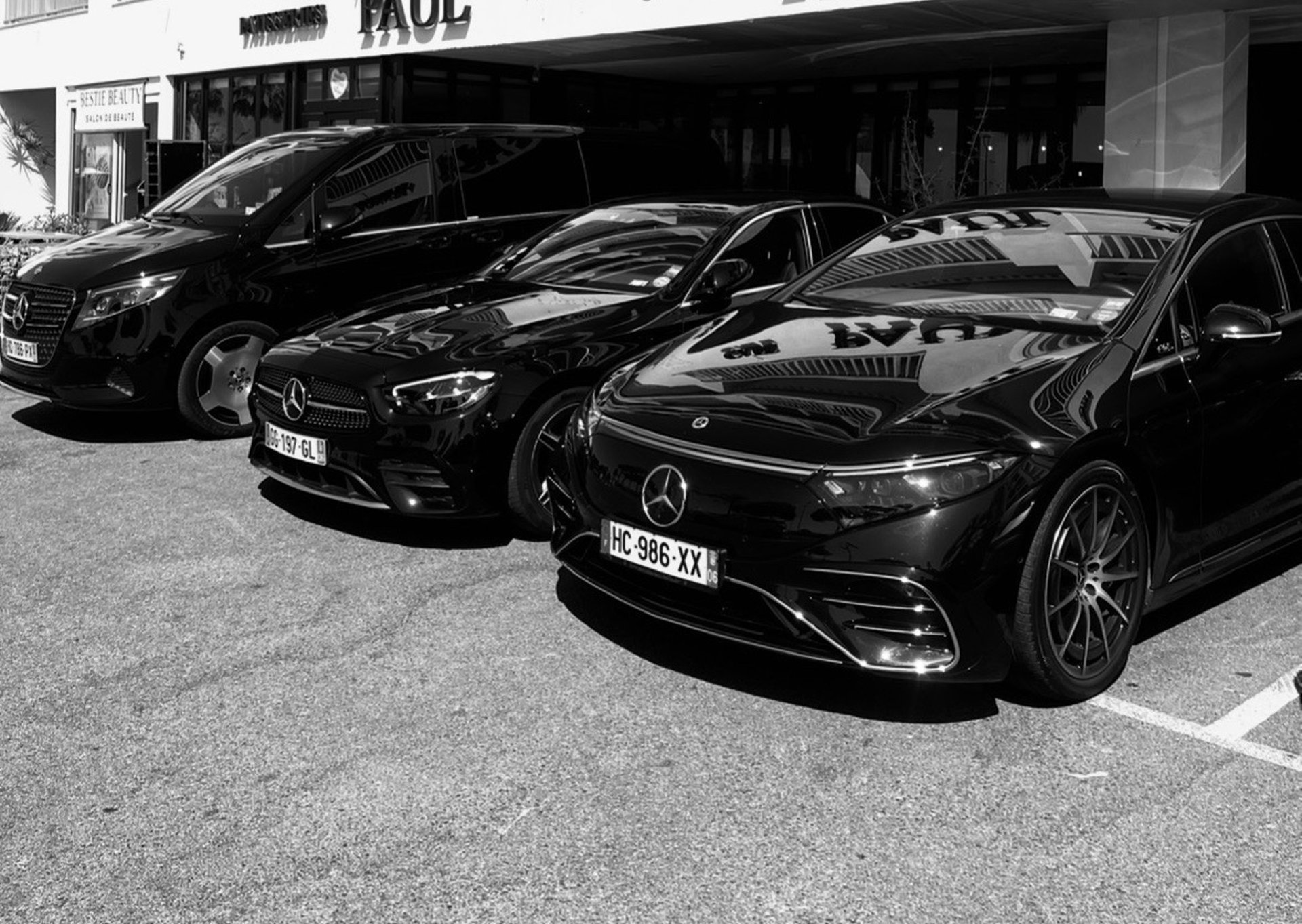 A black luxury sedan parked on a leaf-covered road.