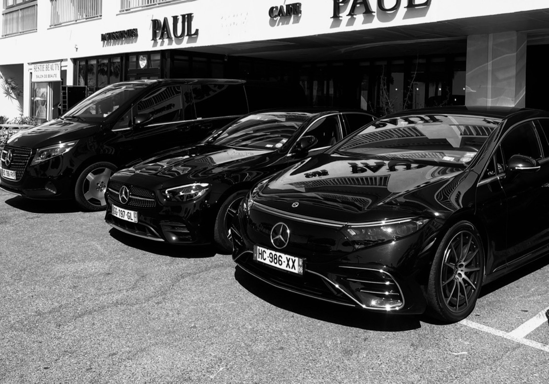 A black luxury sedan parked on a leaf-covered road.